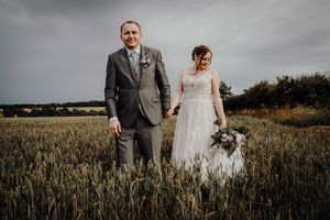 Georgie and James holding hands in the wheat field behind Huntsmill Farm gardens. Photo thanks to Sam and Steve Photography.